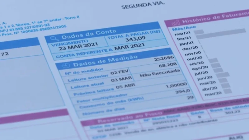 Pessoa segura conta de luz detalhada com valores de consumo e vencimento em destaque.